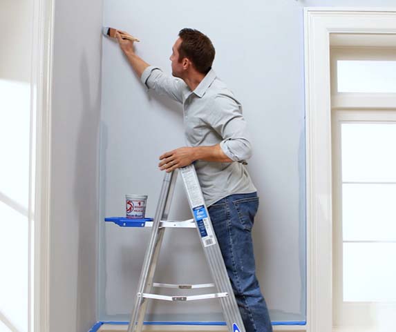 hombre pintando en una escalera