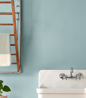 Close-up of a drying rack against a warm blue, Blue Arrow wall with wall-mounted sink.