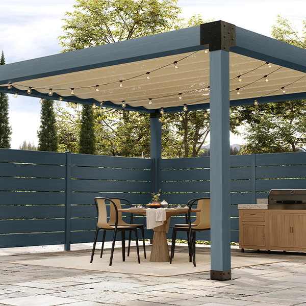 Modern outdoor dining area beneath a pergola with Cottage Door blue-gray architectural elements, blending indoor comfort with outdoor living.