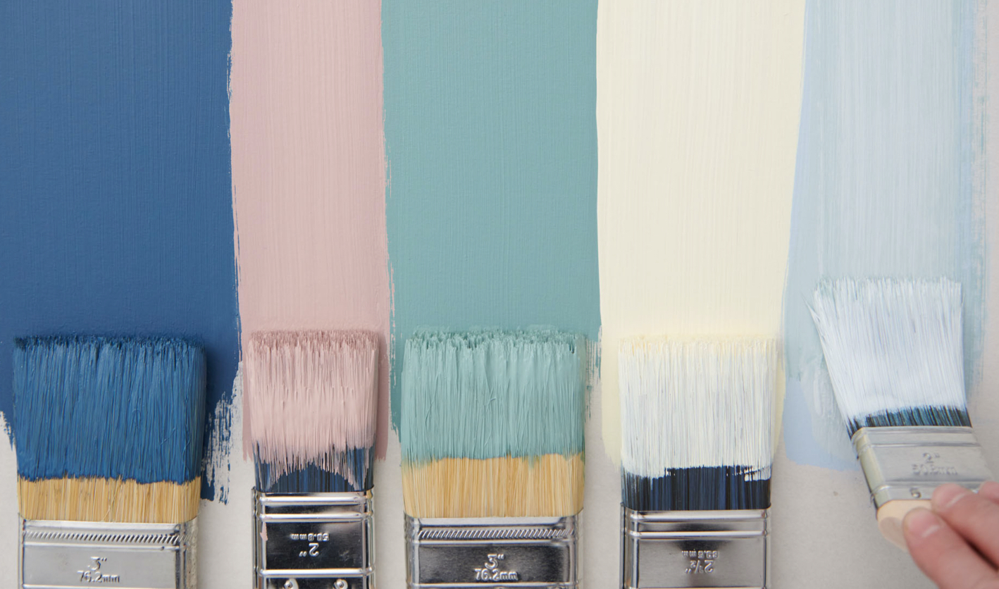 Vertical paint strokes in pastel shades with the paint-soaked bristles of brushes visible at the bottom.