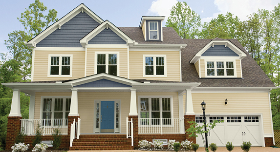 Large house with Antique Buff siding, Crisp Cotton trim, garage door and columns, and Elephant Gray peaked roofs.