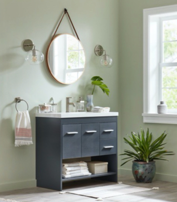 Dusty-green bathroom with dark charcoal gray vanity, large window, plants and round mirror.