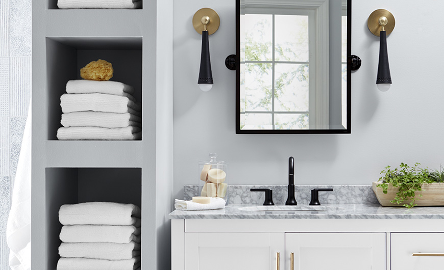 Light gray, black and white color palette in bathroom with modern black fixtures and open linen shelves.