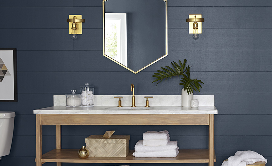 bathroom vanity with gold mirror against a deep midnight blue wall.