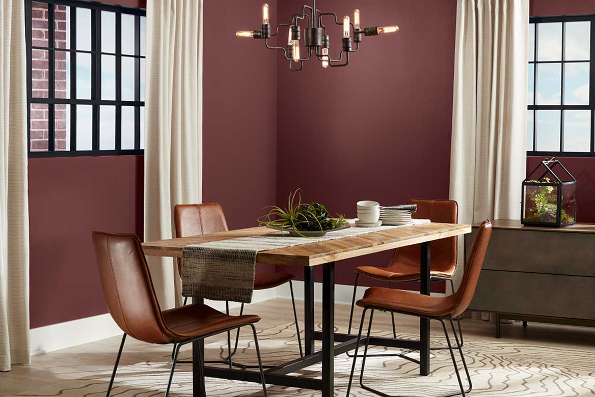 Rustic red dining room with paned windows, modern leather chairs and industrial light fixture.