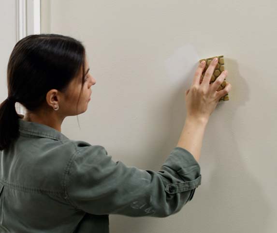 mujer lijando una pared